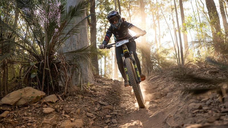A cyclist rides downhill on a trail.