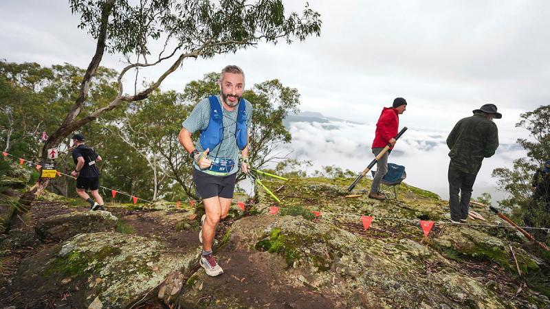 Several men on a running trail in the mountains.
