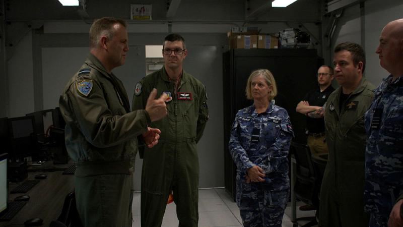 A group of military personnel standing around in a room talking.