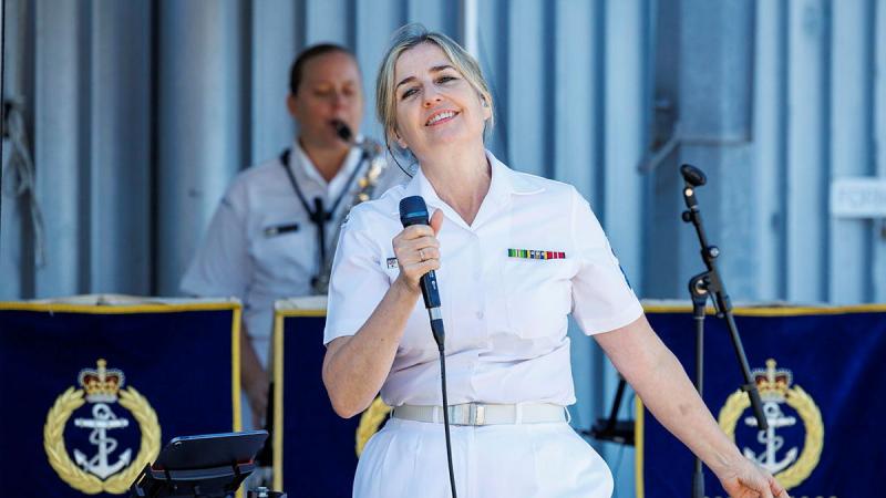 A woman stands on stage with a microphone.