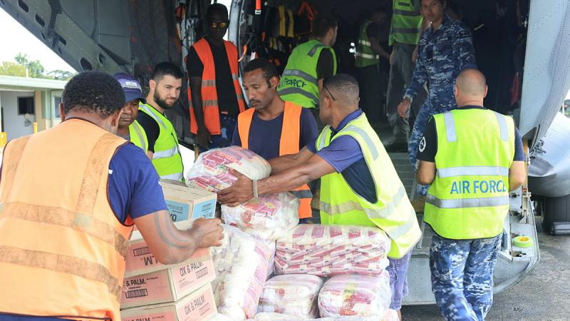 People in high-vis vests load supplies into the hull of an aircraft.