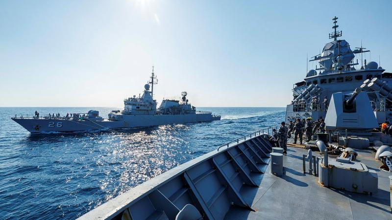 Two ships side by side in the open ocean.