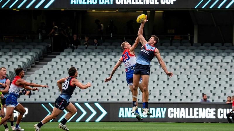 Two football players leap for the ball during a game.
