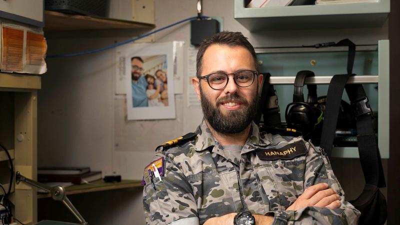 A sailor stands with his arms crossed. 