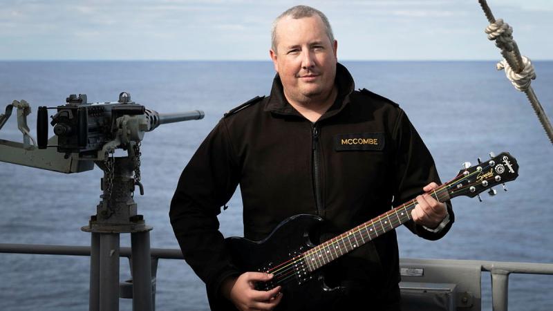 Chief Petty Officer Boatswain William McCombe with his electric guitar on the upper deck of HMAS Ballarat while at sea.