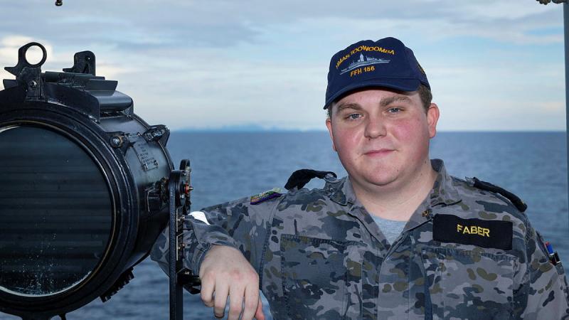 A man stands on a ship at sea.