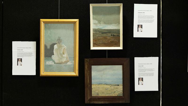 Oil paintings hang on a black wall.