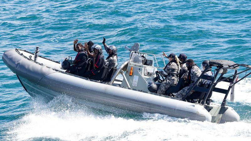 People wave from a boat at sea.
