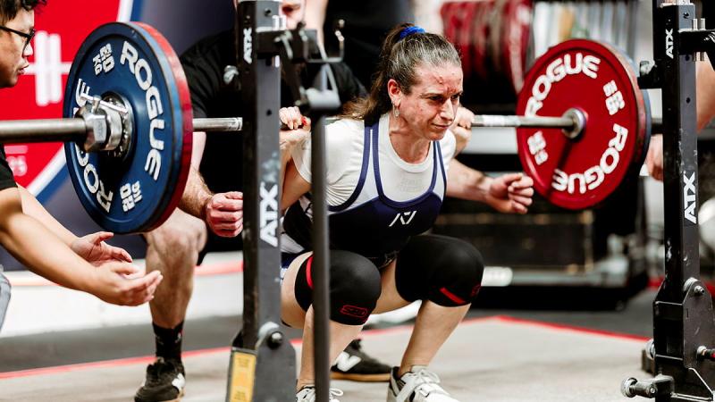 A woman performs a barbell squat.