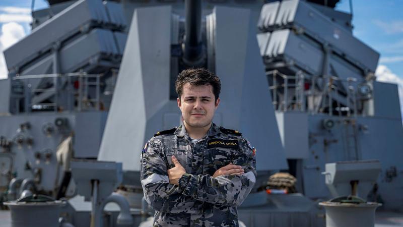 A man stands on a ship with his arms folded. 