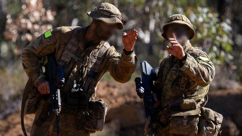 Two Army members in full uniform direct with hand signals.