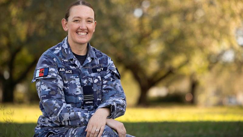 A woman in Air Force uniform sitting down smiling at the camera.