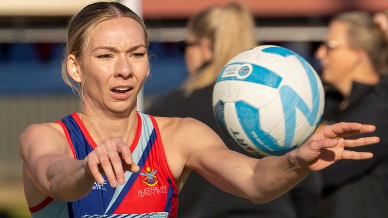 A female netball player throws a ball.