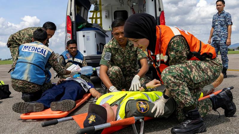 Malaysian army medics assist a simulated injured aviator on a stretcher.