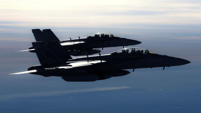 Two jets flying side by side in the sky.