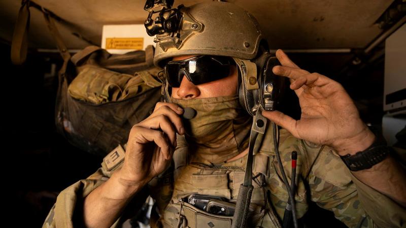Close-up of a soldier in battle gear talking into a radio mic.