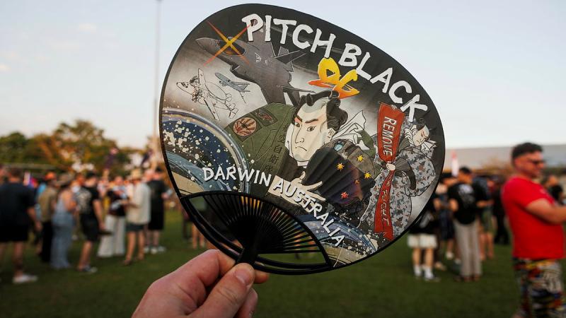 A handheld paper fan decorated with Japanese art and the words 'Pitch Black'.