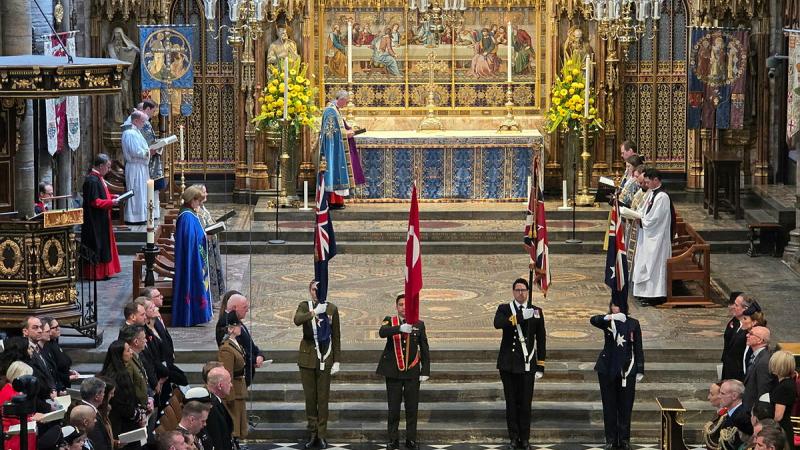 Clergy gather around a cathedral altar with military personnel holding flags in front.