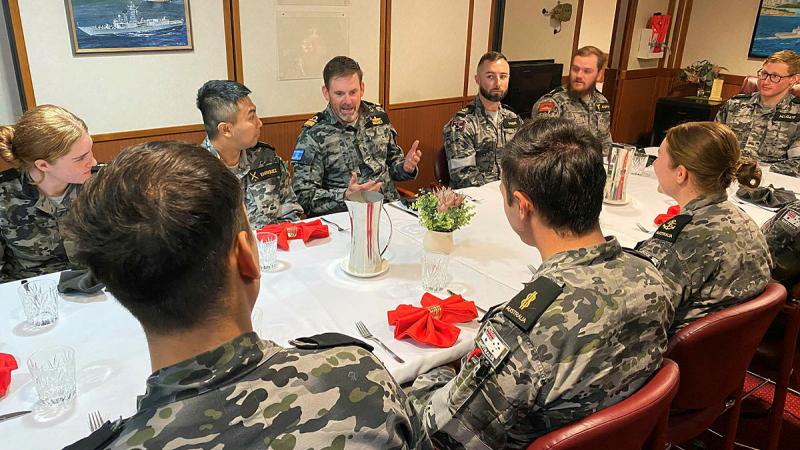 Sailors sit around a dining table.