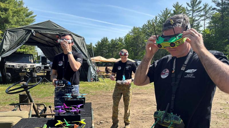 Three men putting on VR goggles connected to drones.