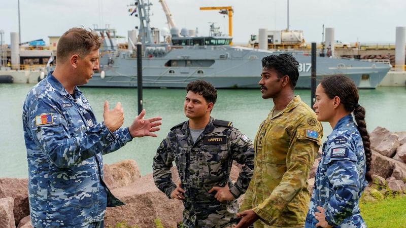 A man talks to three other people, all in military uniforms.