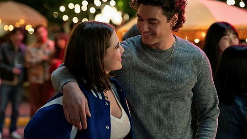 A young man and woman put an arm around each other and look into each other's eyes.