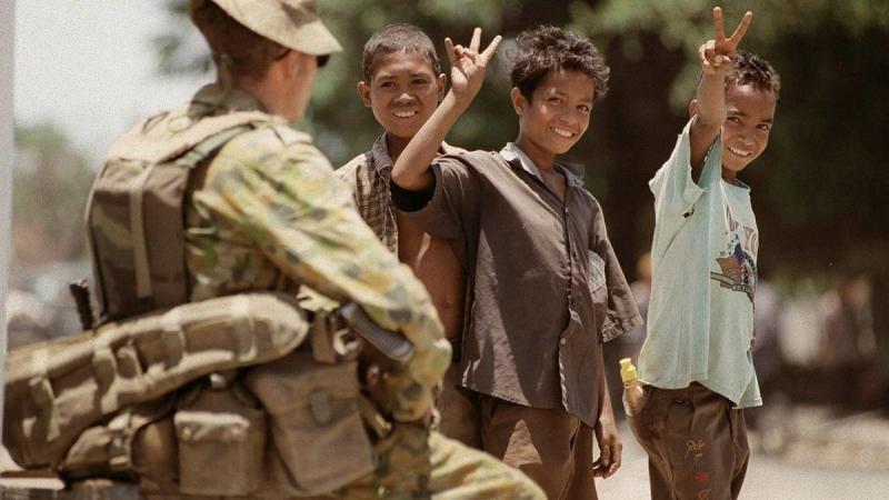 Timorese boys give a peace sign to an Australian Army soldier.