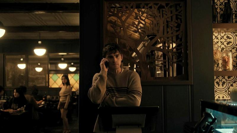 A man standing in a restaurant while talking on the phone.