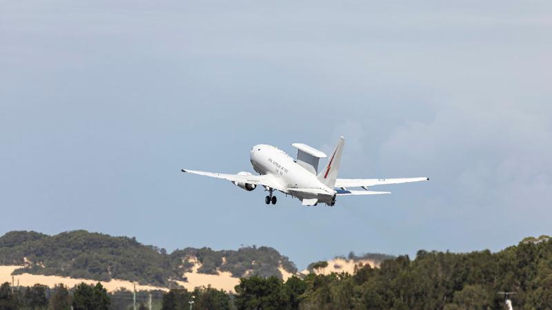 An aircraft flies into the sky past mountains.