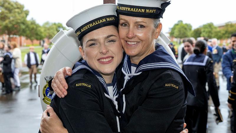 Two woman in Navy uniform embrace and smile.