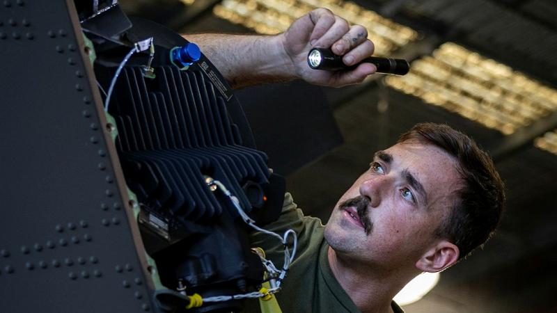 A man shines a torch into an exposed engine.