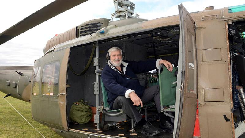 A man sits in the rear of a military helicopter.