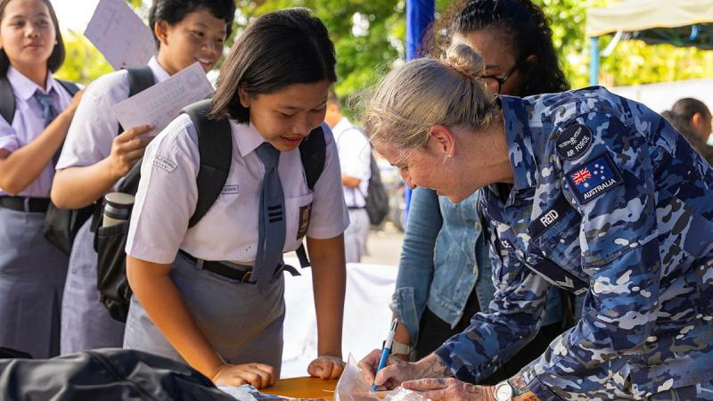 An Air Force member writes down information while Indonesian locals watch.