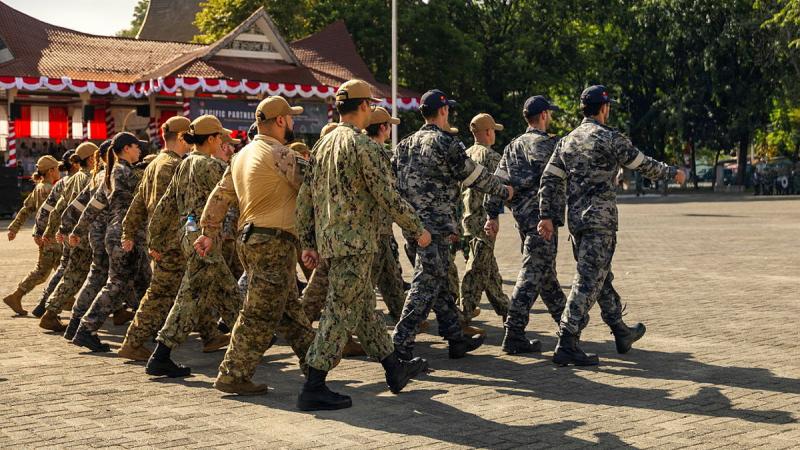 A group of military personnel from varied countries march together. 