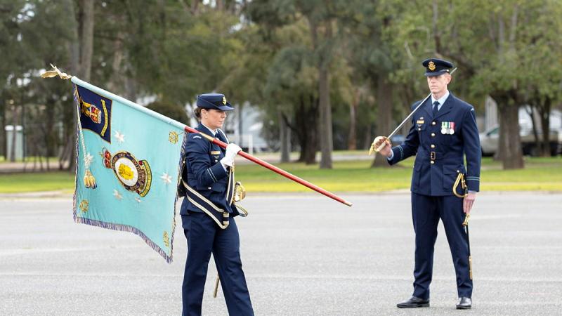 Two military personnel, one with a flag and the other with a sword.