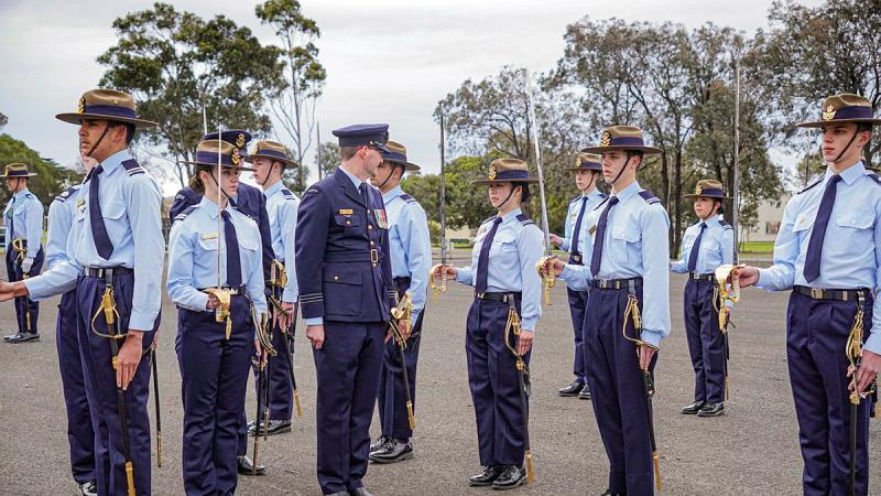 An Air Force leader inspects a row of cadets who stand on parade.