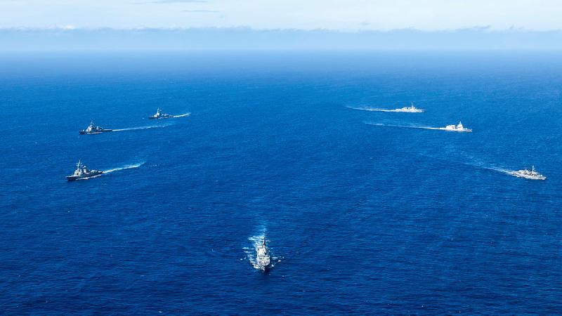 Seven ships sail away from each other out at sea.