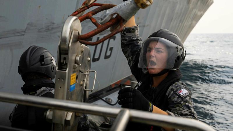 A sailor connects a hook at sea.
