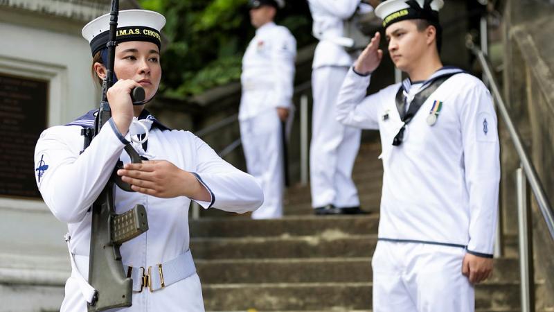 Sailors stand to attention on the staircase.