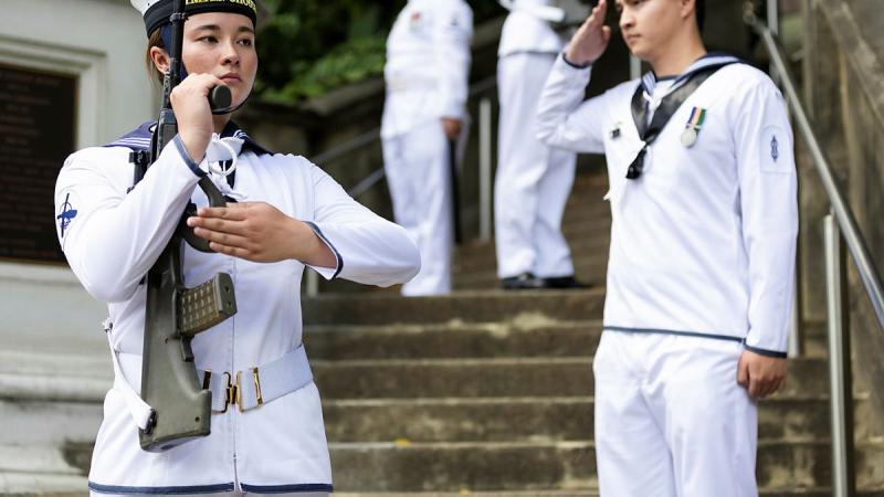 Sailors stand to attention on the staircase.