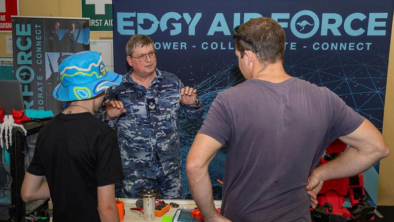A military member from EDGY Air Force speaks to civilians at a pop-up desk.