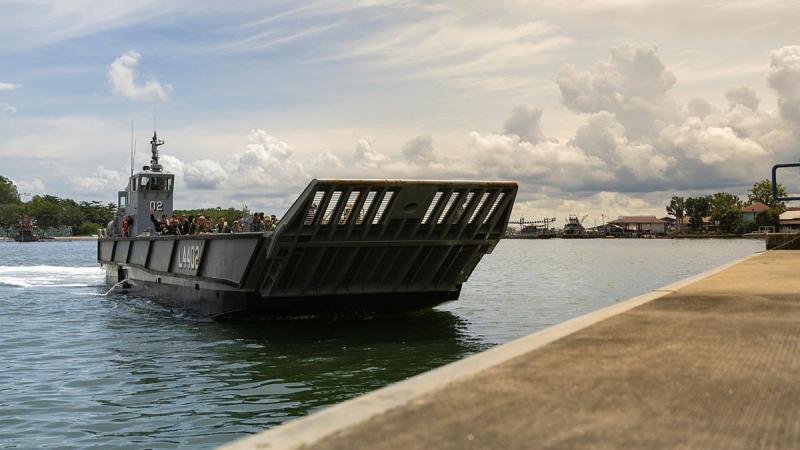 A landing craft is shown close to shore on a partly cloudy day.