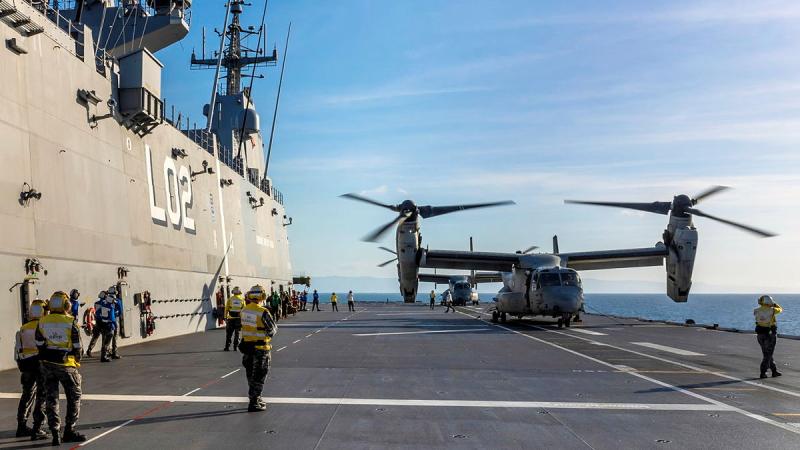 United States Marine Corps MV-22 Osprey aircraft and Royal Australian Navy personnel on the flight deck of HMAS Canberra, preparing for flying operations.