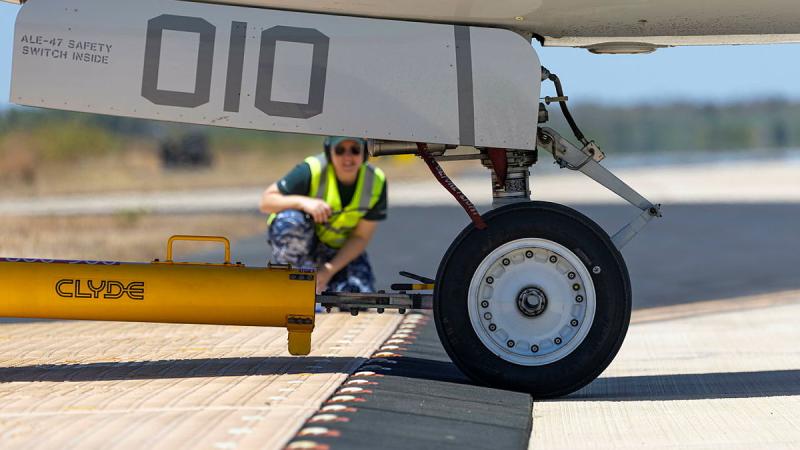 A person in high-vis watches as the wheel of a vehicle passes over a small ramp.