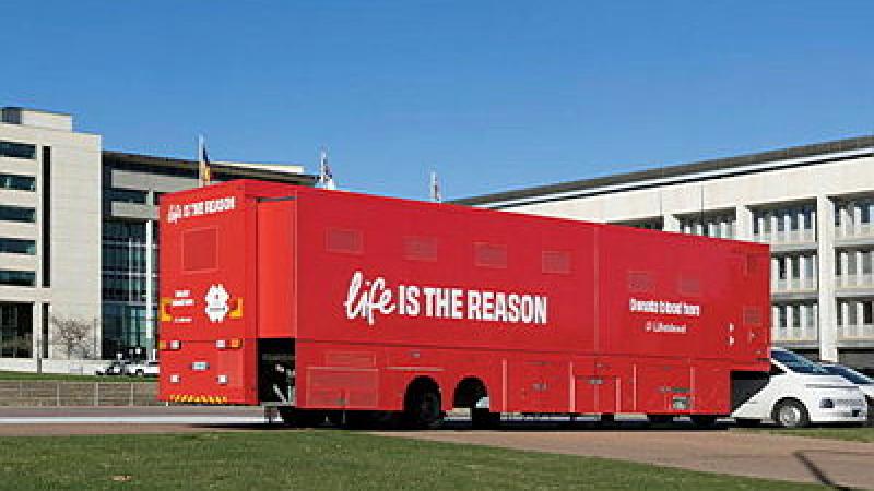 Red van for blood donation parked outside office buildings