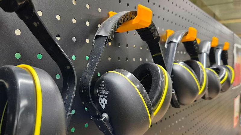 A pegboard rack holds a collection of black and yellow headphones.