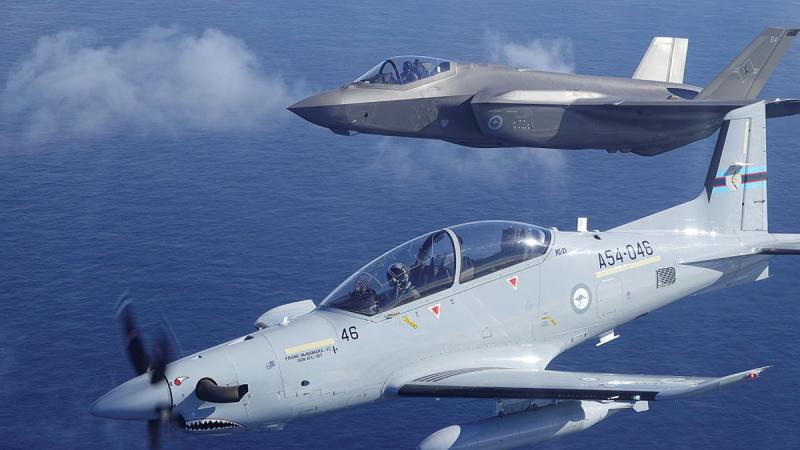 Two different aircraft fly close together in a mostly clear sky.