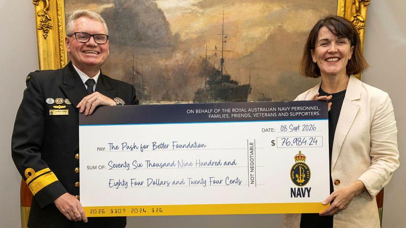 A military man and a civilian woman hold a cheque for The Push for Better Foundation