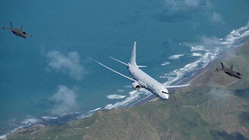 Three aircraft fly over a shoreline.