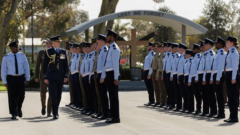 Three military men survey two rows of younger military personnel.